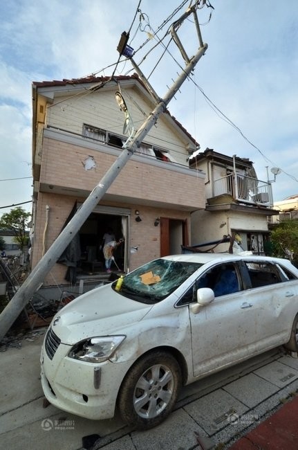 9月2日,在日本琦玉县越谷市,被龙卷风吹倒的电线杆斜在一栋房屋前.