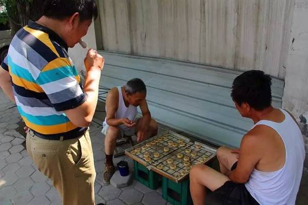 两位大爷下象棋,旁边大叔吃康乐小豆.