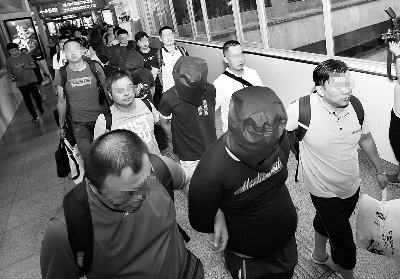 昨晚,诈骗团伙的8名犯罪嫌疑人戴头套者被押解回京摄/记者 黑克