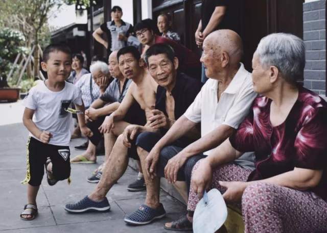 2017年7月13日,重庆奉节白帝城。一名男孩从坐在路沿上歇息的一排老人面前跑过。海军准将