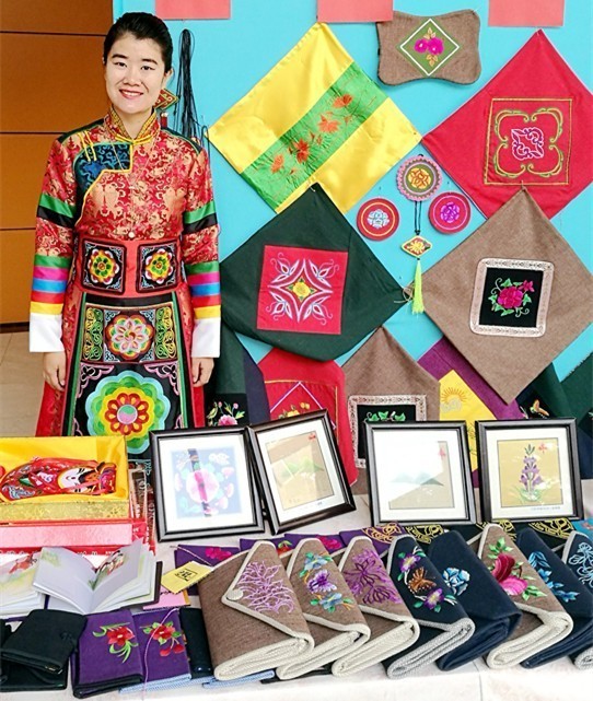 曾 △ 身着土族服装的作者与来自家乡的刺绣作品合影