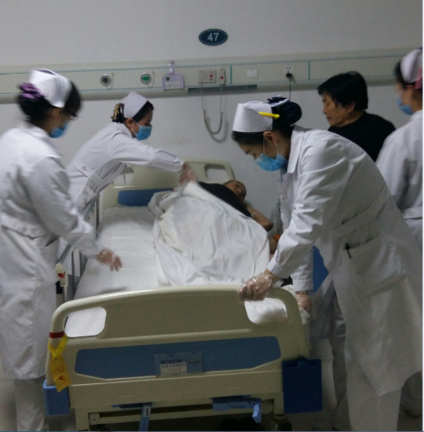 护士们帮助老年患者在病床上翻身