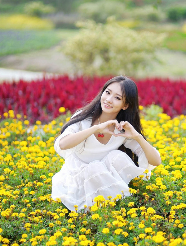 在公园花海边玩耍的漂亮白衣少女姑娘!