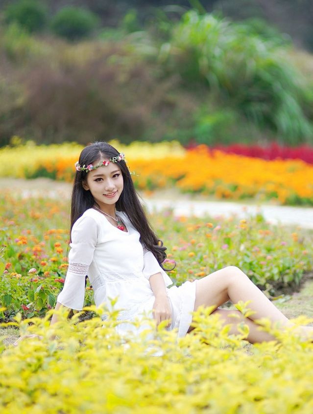 在公园花海边玩耍的漂亮白衣少女姑娘!