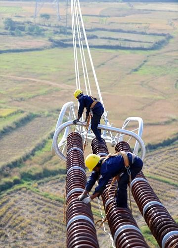 10月5日,施工人员在江西省丰城市同田乡50米高空安装输电铁塔附件
