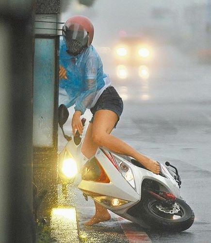 屏东恒春街头一名女骑士被强风吹往路旁,几乎抓不住摩托车.台湾媒体