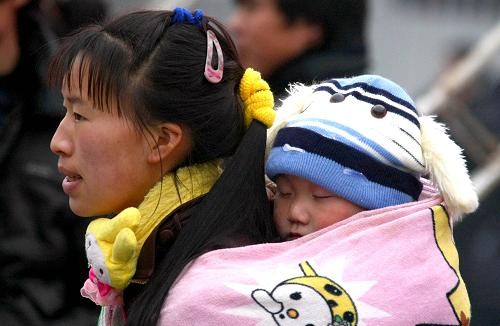 1月8日,在成都火车站,一位小朋友在妈妈背上等待进站乘车.