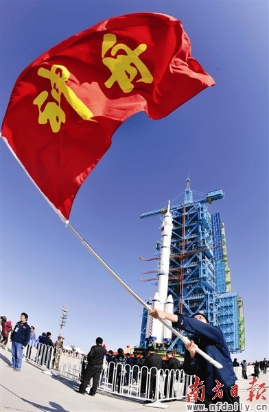 酒泉发射中心一位工作人员挥舞起写有"神舟"大字的红旗庆贺阶段性胜利