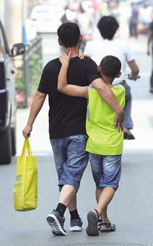 在一辅导班附近,一位父亲正搂着孩子前往辅导班