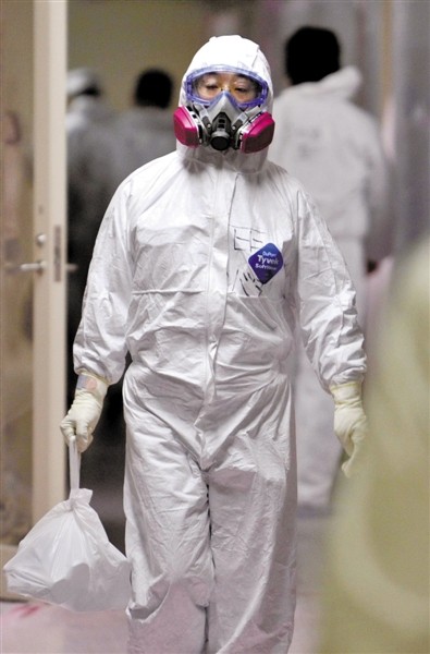 头戴防护面具的记者在东京电力公司员工的指引下进入福岛第一核电站