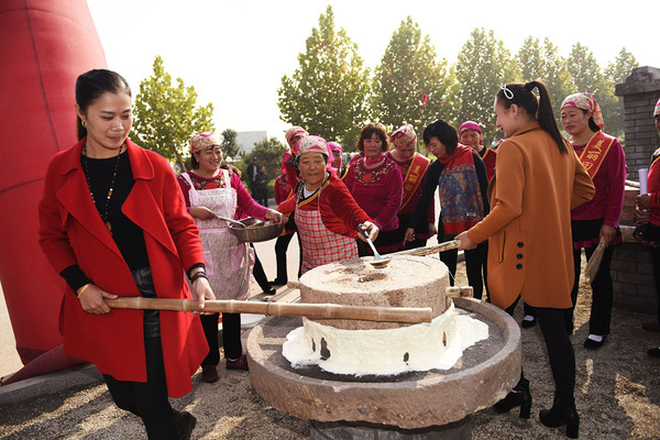 人们在体验推石磨磨豆浆的乐趣.