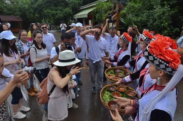 热情好客的彝族朋友抬着自家酿玉米酒在寨子门口迎接大家
