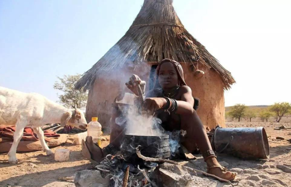 一个辛巴族的孩子在房前做饭