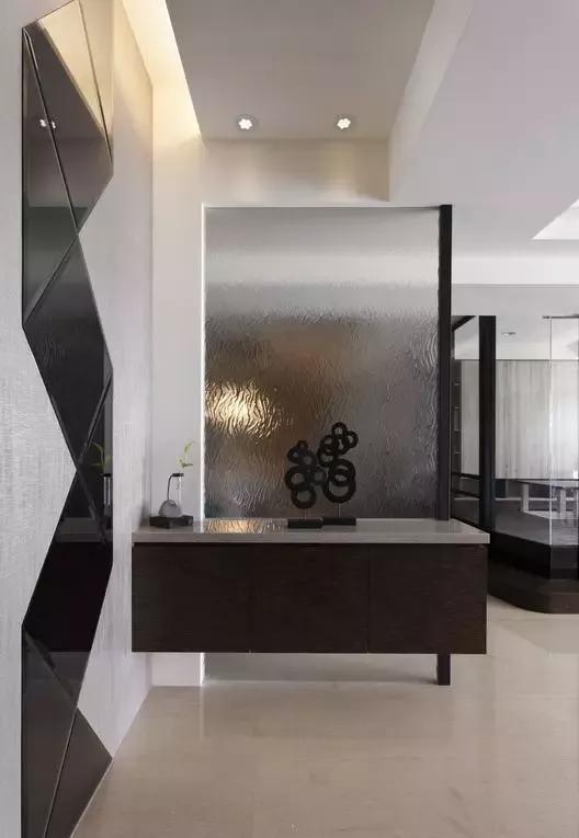 设计师以半透明玻璃隔开玄关与用餐区,玄关的几何镜面让空间不会有