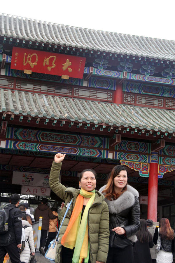 这位妈妈在女儿的陪伴下来大明湖游玩,兴奋的在景区门口摆姿势拍照.