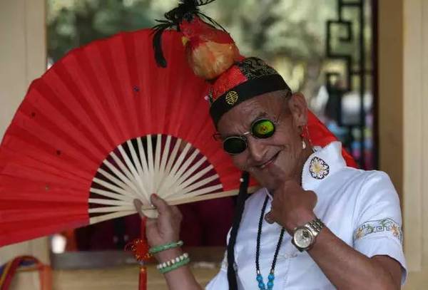 他总是身穿各式各样的旗袍或裙子,脚踩高跟鞋,戴着戒指,项链,耳环